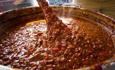 Spoon stirring chili in pot